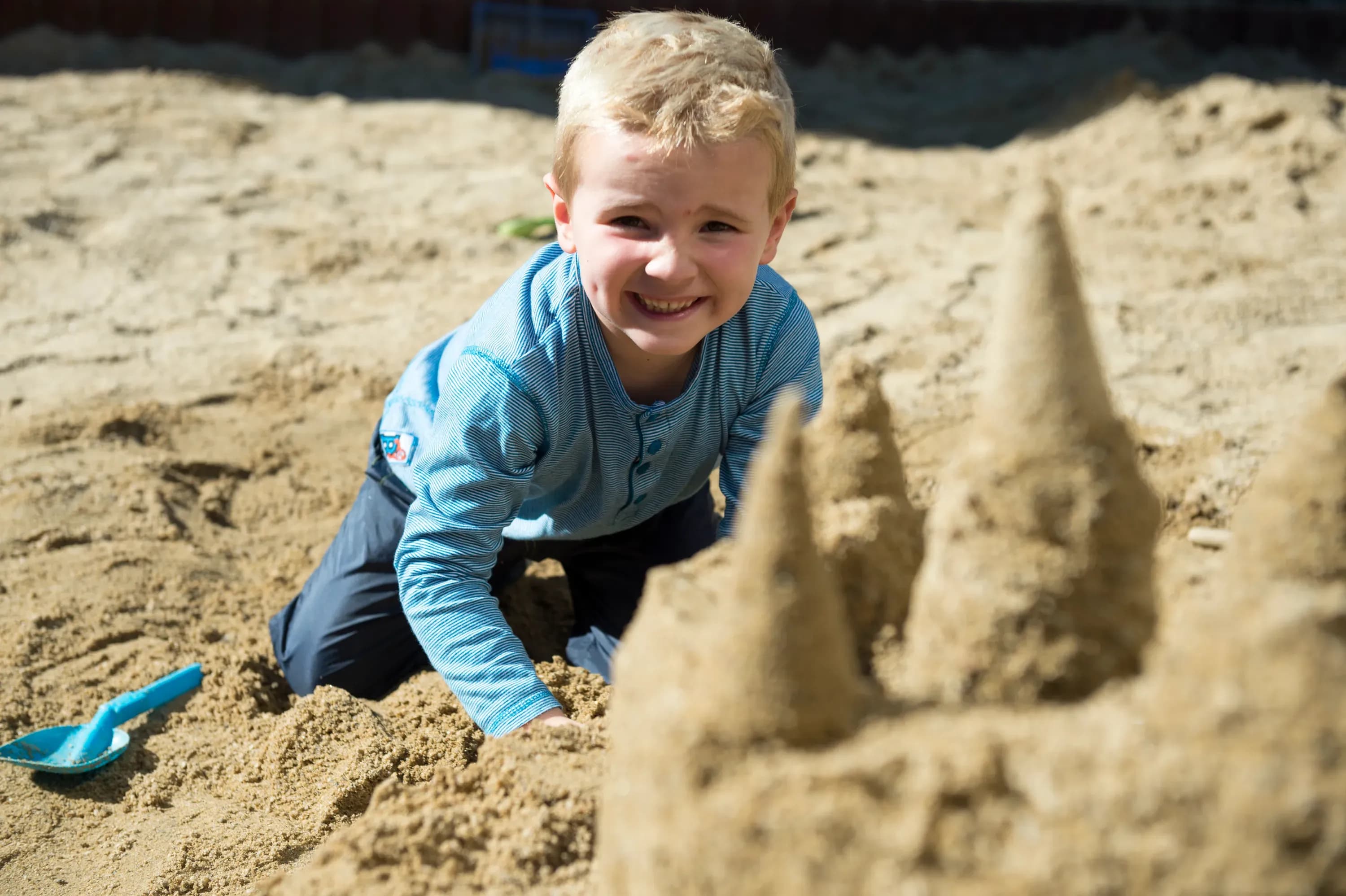 Fröhlicher Junge beim spielen im Sandkasten im Familienhotel Schreinerhof