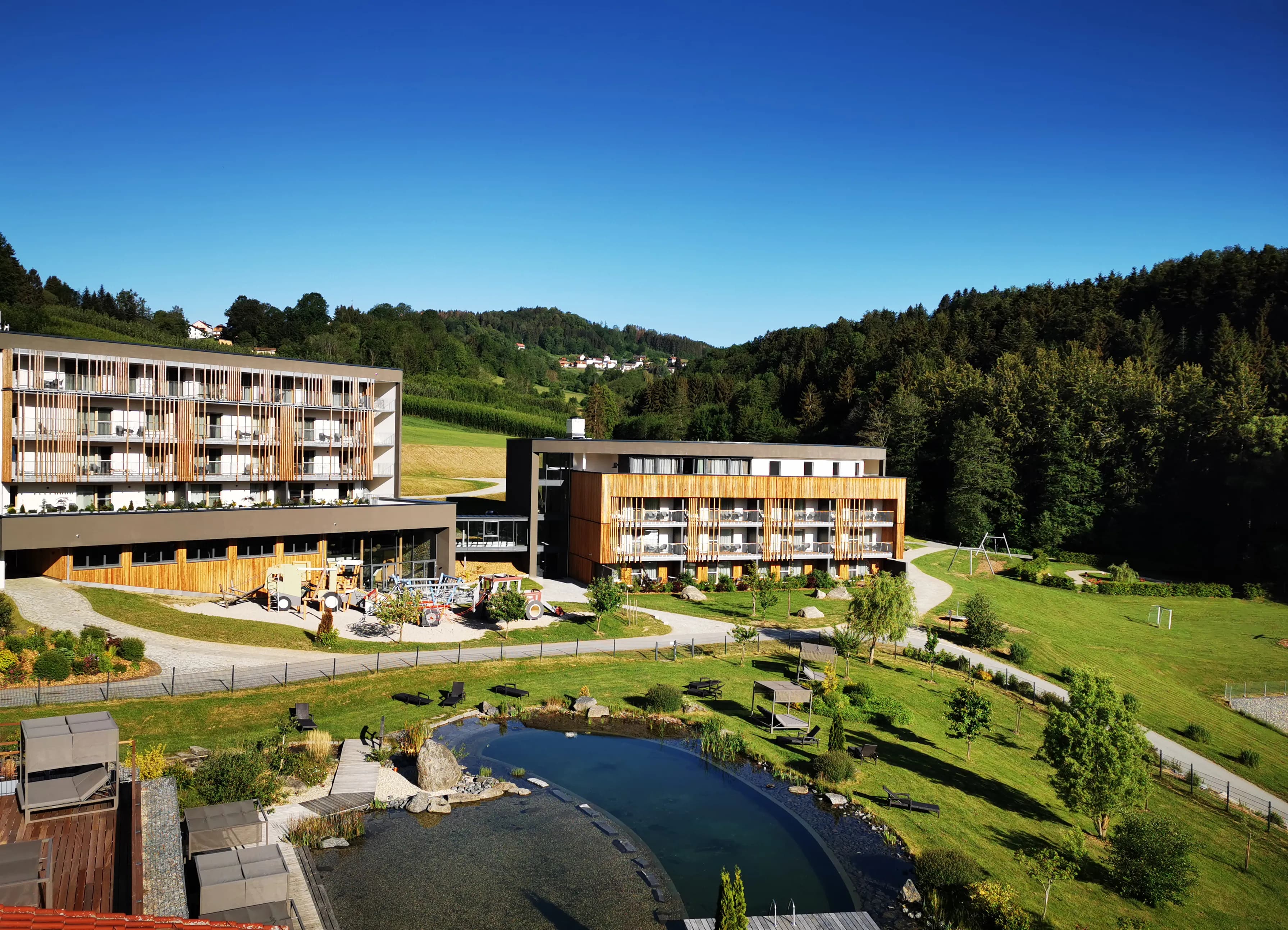 Blick auf das Familienhotel Schreinerhof mit dem Bayerischen Wald im Hintergrund 