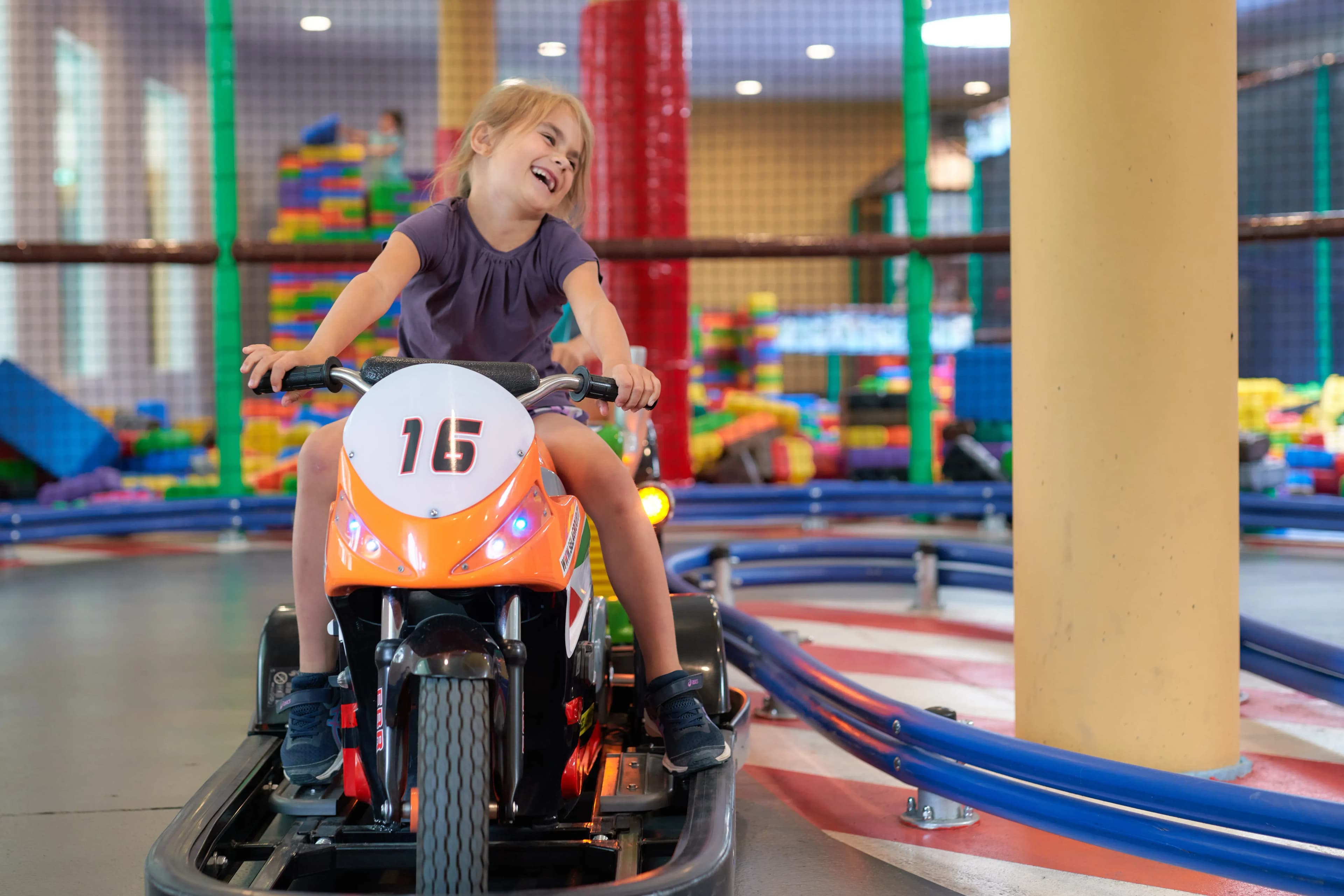 Fröhliches Mädchen auf der Indoor-Kartbahn im Familienhotel Schreinerhof