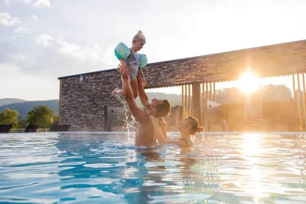 Familie im Sky-Pool des Familienhotels Schreinerhof bei Sonnenuntergang