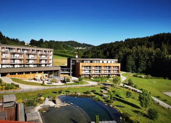 Blick auf das Familienhotel Schreinerhof mit dem Bayerischen Wald im Hintergrund