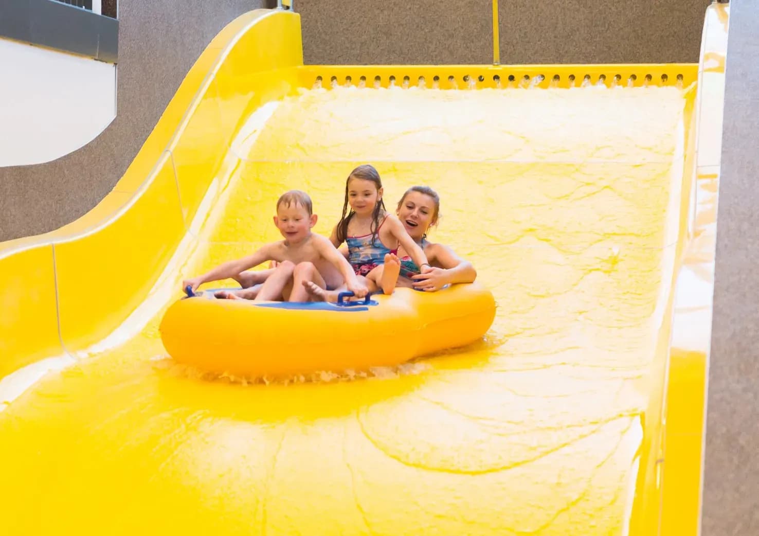 Kinder rutschen lachend die Wasserrutsche im Familienhotel Schreinerhof im Bayerischen Wald hinunter.