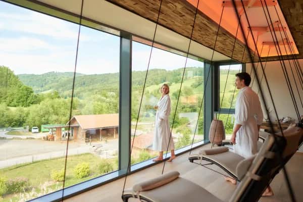 Eltern entspannen im Wellnessbereich, während Kinder im Familienhotel Schreinerhof spielen und betreut werden.